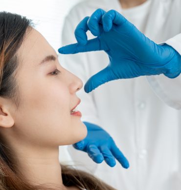 doctor examines patient nose before rhinoplasty